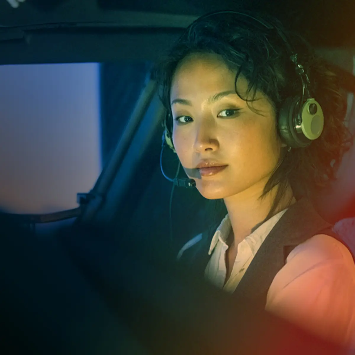 Closeup of a young woman wearing a headset with a boom mic, piloting a plane