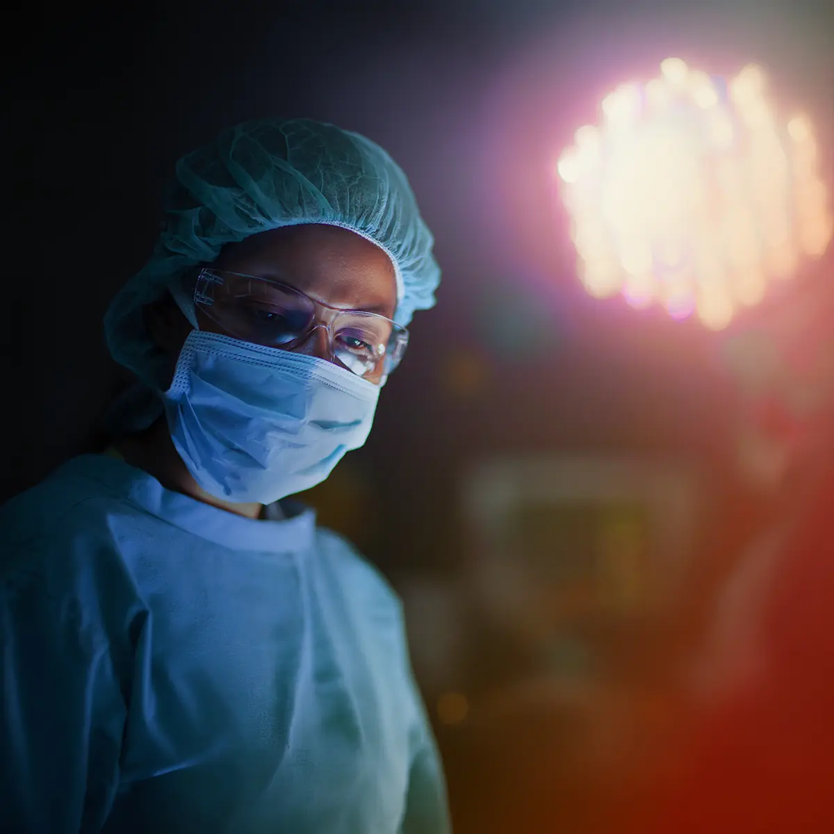 Closeup of a young man wearing surgical scrubs, hairnet and face mask.